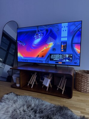 A flat-screen TV on a wooden stand with a space-themed display, a wooden cabinet below, and a fluffy grey rug on the floor. - Artist's Apartment in Manhattan (New York)
