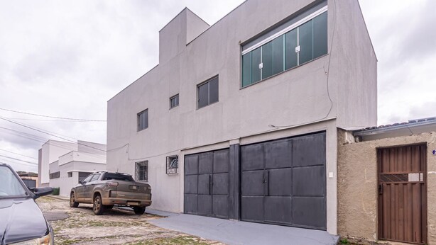 A modern building with a garage, a parked truck, and a gated entrance. - Apto Para 5 Pessoas com Garagem e Churrasqueira (Para de Minas)