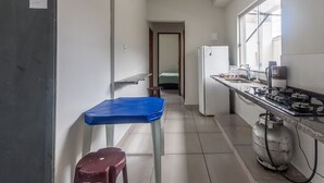 A narrow kitchen with a gas stove, a refrigerator, and a gas cylinder. - Apto Para 5 Pessoas com Garagem e Churrasqueira (Para de Minas)