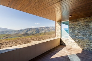 Una habitación moderna con un ventanal grande, pared de piedra y techo de madera.