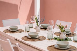 Una mesa de comedor puesta con cuencos, vasos y un jarrón con flores.