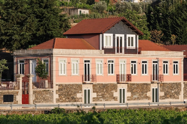 Ein zweistöckiges Gebäude mit einer Stein-Fassade, zahlreichen Fenstern und einem roten Ziegeldach.