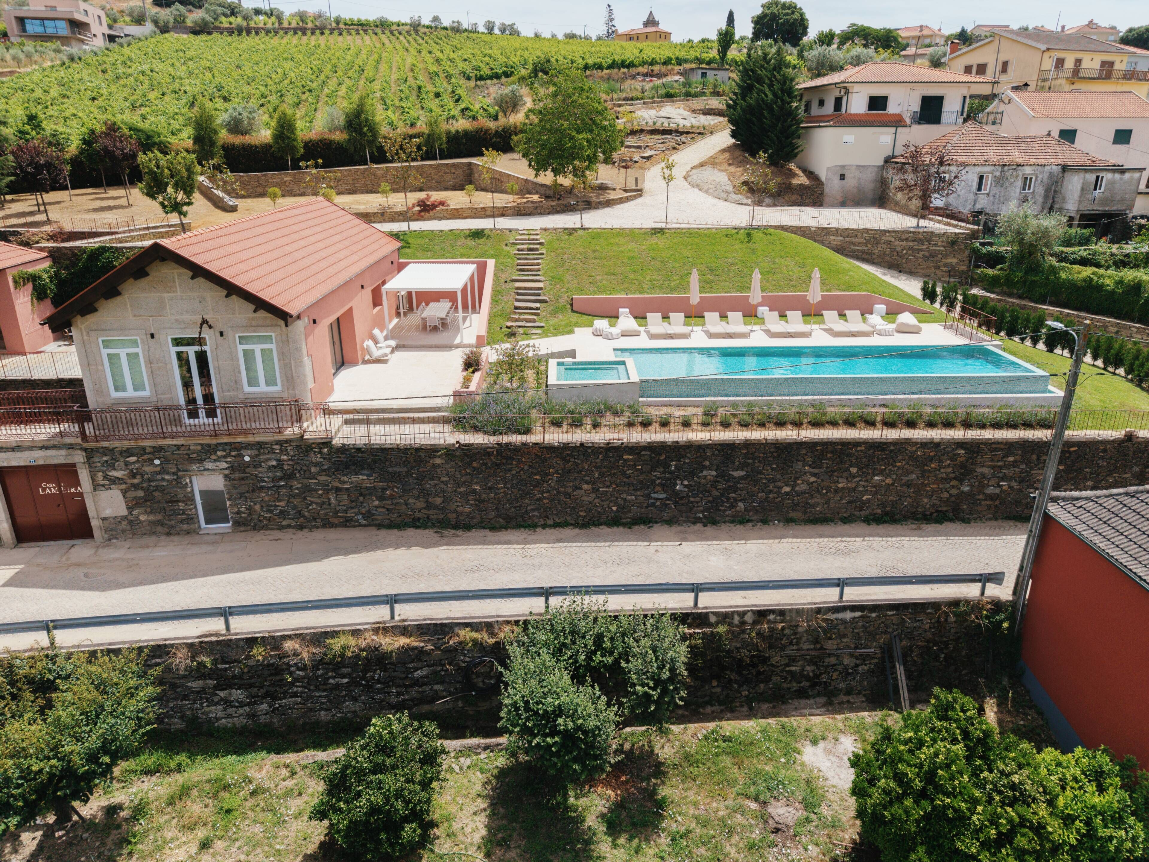 Una villa con piscina, muros de piedra y un viñedo al fondo.