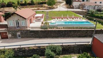 Una villa con piscina, muros de piedra y un viñedo al fondo.