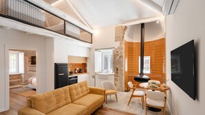 Ein modernes Interieur mit einer Couch, einem Esstisch, Stühlen, einer Küchenzeile und einem an der Wand montierten Fernseher.