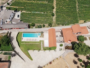 An aerial view of a property with a swimming pool, a large building with a red roof, and adjacent green fields. - Casa da Francelina - Douro Valley (Peso da Régua)