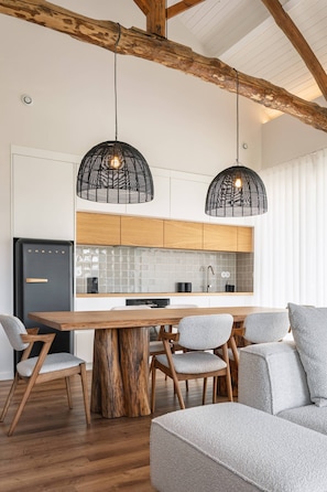 Una cocina moderna con una mesa de comedor de madera, sillas e iluminación colgante.