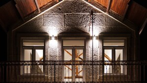 Un bâtiment doté d’une façade en pierre, de poutres en bois et d’un balcon orné de rampes en métal ouvragé.