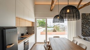 A modern kitchen with a built-in refrigerator, wooden cabinets, and a dining area with a table and chairs.