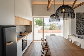 Een moderne keuken met een ingebouwde koelkast, houten kastjes en een eethoek met een tafel en stoelen.