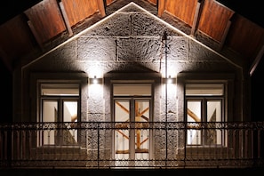 Een gebouw met een stenen gevel, houten balken en een balkon met sierlijk metalen hekwerk.