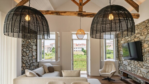 A modern living room with a stone wall, a sofa, a TV, and two hanging lights.