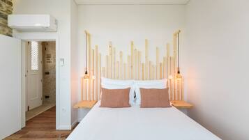Un dormitorio con cama, cabecera de madera, lámparas de noche y aire acondicionado instalado en la pared.