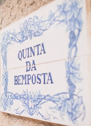 A tiled wall with the inscription 'QUINTA DA BEMPOSTA' surrounded by floral patterns. - Casa do Alambique in Quinta da Bemposta (Vila Nova de Famalicão)