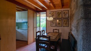 A dining area with a table, chairs, a chandelier, and framed botanical prints on the wall. - Casa do Alambique in Quinta da Bemposta (Vila Nova de Famalicão)