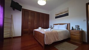 Ein Schlafzimmer mit einem hölzernen Bett, einem Nachttisch, einer Kommode, einem Kleiderschrank und einem Gemälde an der Wand.