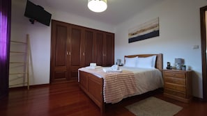 Ein Schlafzimmer mit einem hölzernen Bett, einem Nachttisch, einer Kommode, einem Kleiderschrank und einem Gemälde an der Wand.