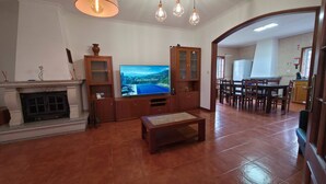 Ein Wohnzimmer mit Kamin, Fernseher, Holz-Unterhaltungseinheit, Esstisch und Stühlen.