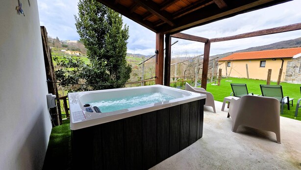Un jacuzzi en un espacio exterior con vistas a un césped verde y un edificio al fondo.