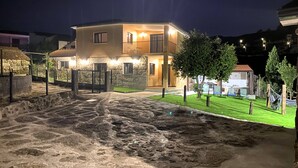Una casa de dos pisos con balcón, entrada de adoquines y césped bien cuidado.
