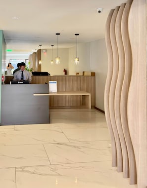 Ein Empfangsbereich mit modernem Design, einer hölzernen Bank und Pendelleuchten.