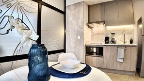 A modern kitchen with a marble backsplash, stainless steel appliances, and a dining area with a white orchid in a blue vase. - Modern Studio by La Carolina Park & Metro +Free WIFI (Quito)