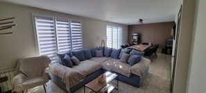 Ein Wohnzimmer mit einer Eckcouch, einem Esstisch mit Stühlen und einem Deckenventilator.