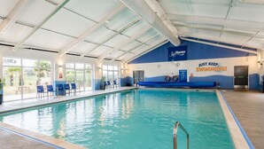 Une piscine intérieure aux murs bleus et blancs, un poste de surveillance pour les maîtres-nageurs et un panneau sur lequel on peut lire : « Continuez à nager ! ».