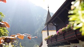 Une vue sur la montagne, avec le clocher d’une église et un bâtiment orné de jardinières fleuries.