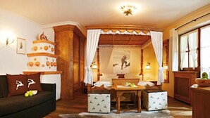 Une pièce chaleureuse avec un plafond en bois, un canapé agrémenté de coussins à motifs, une petite table avec des pommes et un élément décoratif mural.