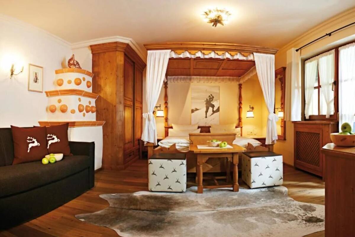 Een gezellige kamer met een houten plafond, een bank met gestreepte kussens, een klein tafeltje met appels en een decoratief object aan de muur.