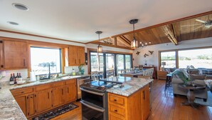 Une cuisine spacieuse avec des meubles en bois, un grand îlot central et un coin repas offrant une vue agréable.