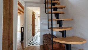 A spiral staircase with wooden steps and black metal railings, leading to an upper floor.
