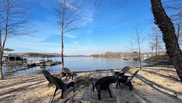 Un cadre idyllique au bord du lac, avec un foyer, des chaises et un quai où sont amarrés des bateaux.