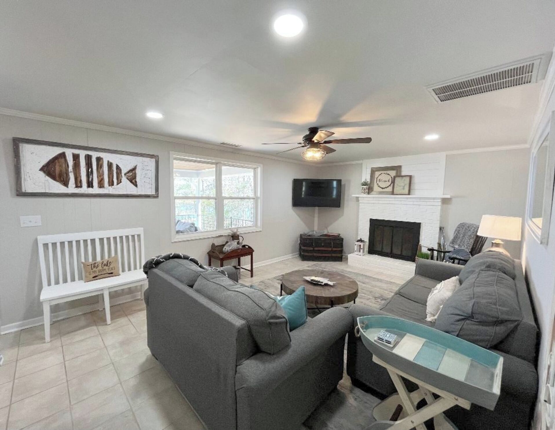 A living room with a sofa, a coffee table, a TV, a fireplace, and a ceiling fan.