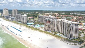 Un hotel sulla spiaggia con diversi edifici alti, una spiaggia sabbiosa e una piscina.