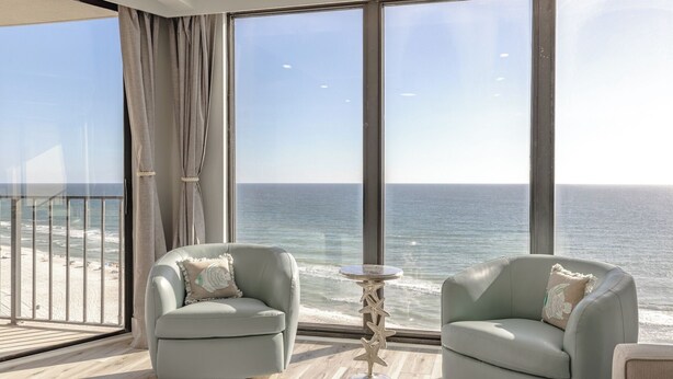Un balcone con due poltrone e un tavolino, vista sulla spiaggia e sull'oceano.