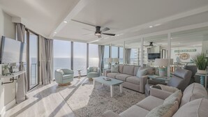 Un soggiorno spazioso con una grande finestra, un ventilatore a soffitto e vista sul mare.