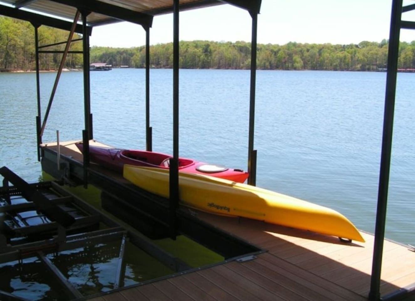 A dock with kayaks and a covered area overlooking a lake.