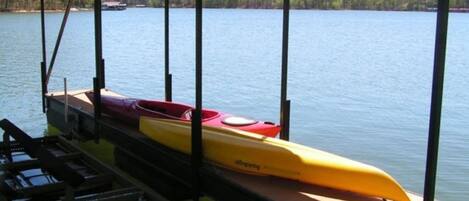 A dock with kayaks and a covered area overlooking a lake.