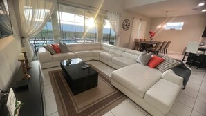 Uma sala de estar moderna com um sofá seccional, uma mesa de centro e um espaço de jantar com cadeiras e uma mesa.