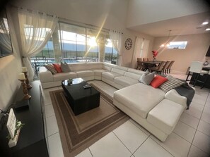 Ein modernes Wohnzimmer mit Ecksofa, Couchtisch und Essbereich mit Stühlen und Tisch.