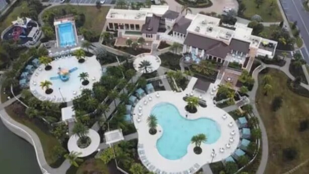 Vista aérea de um resort com várias piscinas, um edifício grande e áreas ajardinadas.