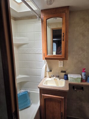 A bathroom with a bathtub, a sink, a mirror, and a shower curtain.