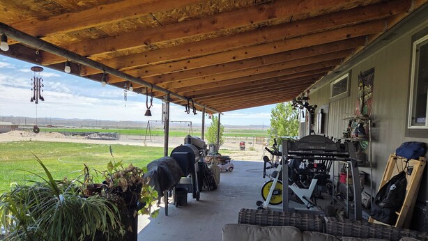 A covered patio with a grill, outdoor seating, and a dog.