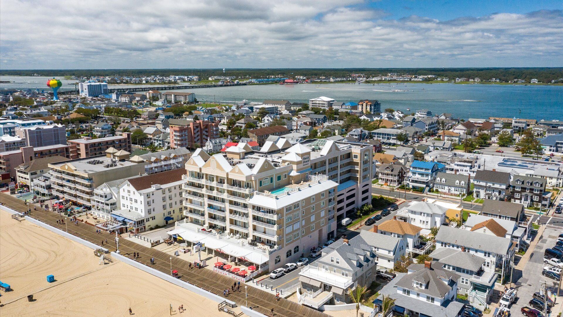 Un pueblo costero con un hotel destacado de varios pisos, una playa y vista al mar.