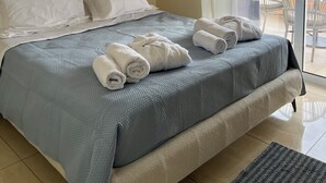 A bedroom with a large bed, a view of the sea through a balcony, and a hanging light fixture. - Seaview Villa Lagonissi |7-min Walk to Beach| Pool & SunsetViews |Athens Riviera (Kalivia Thorikou)