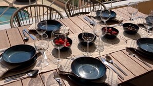 A dining table set for four with wine glasses, plates, and cutlery, overlooking a scenic view of the sea and hills. - Seaview Villa Lagonissi |7-min Walk to Beach| Pool & SunsetViews |Athens Riviera (Kalivia Thorikou)