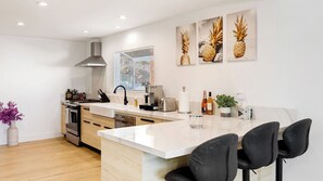 A modern kitchen with a central island, stainless steel appliances, and a window with blinds. - Scenic LA Stay Near Ventura Blvd With Deck, Games, Fireplace & Outdoor Dining Marmol Vista by Avantstay (Woodland Hills)