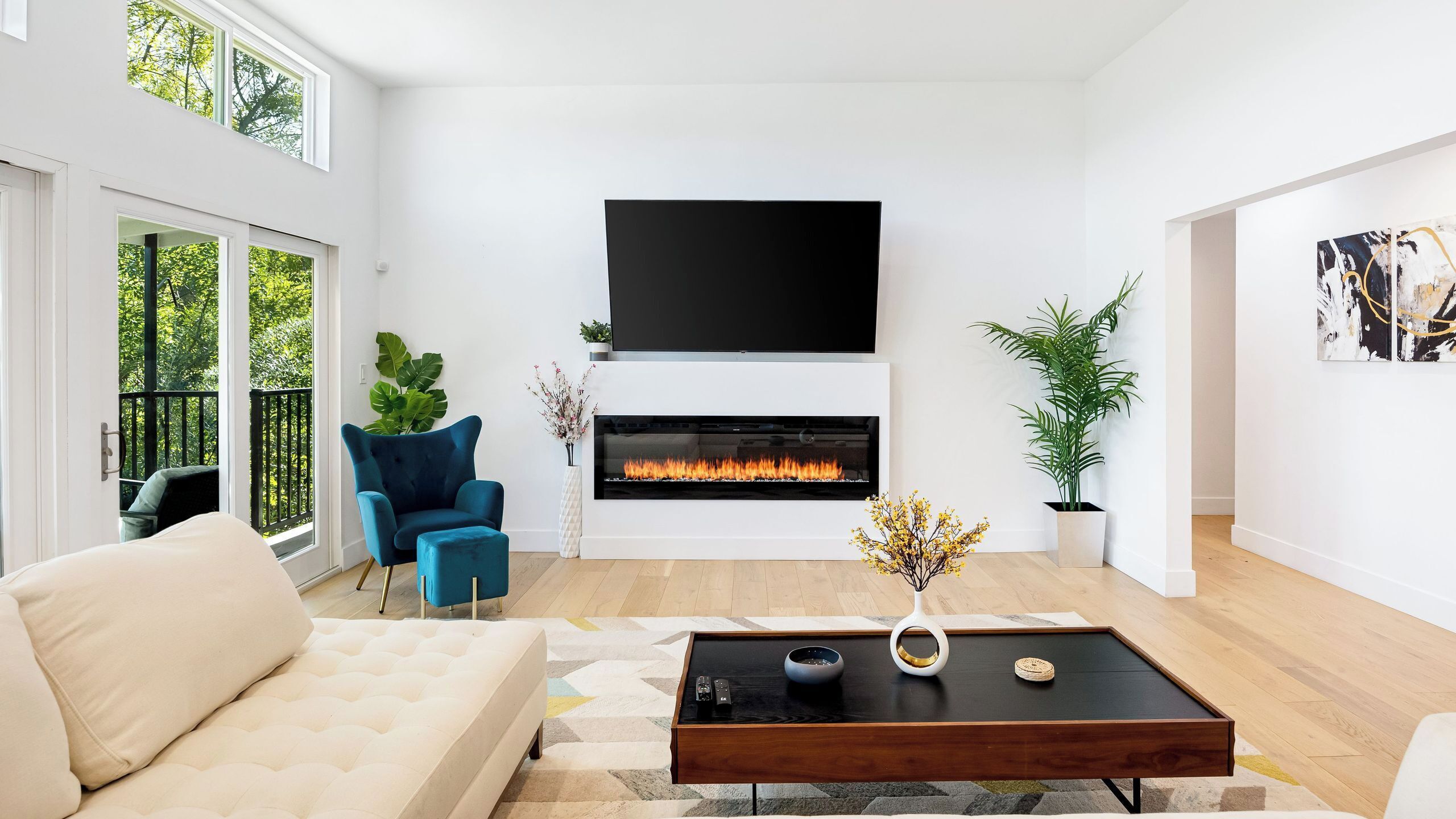 Un salon moderne avec une cheminée, un canapé, une table basse et un téléviseur fixé au mur.